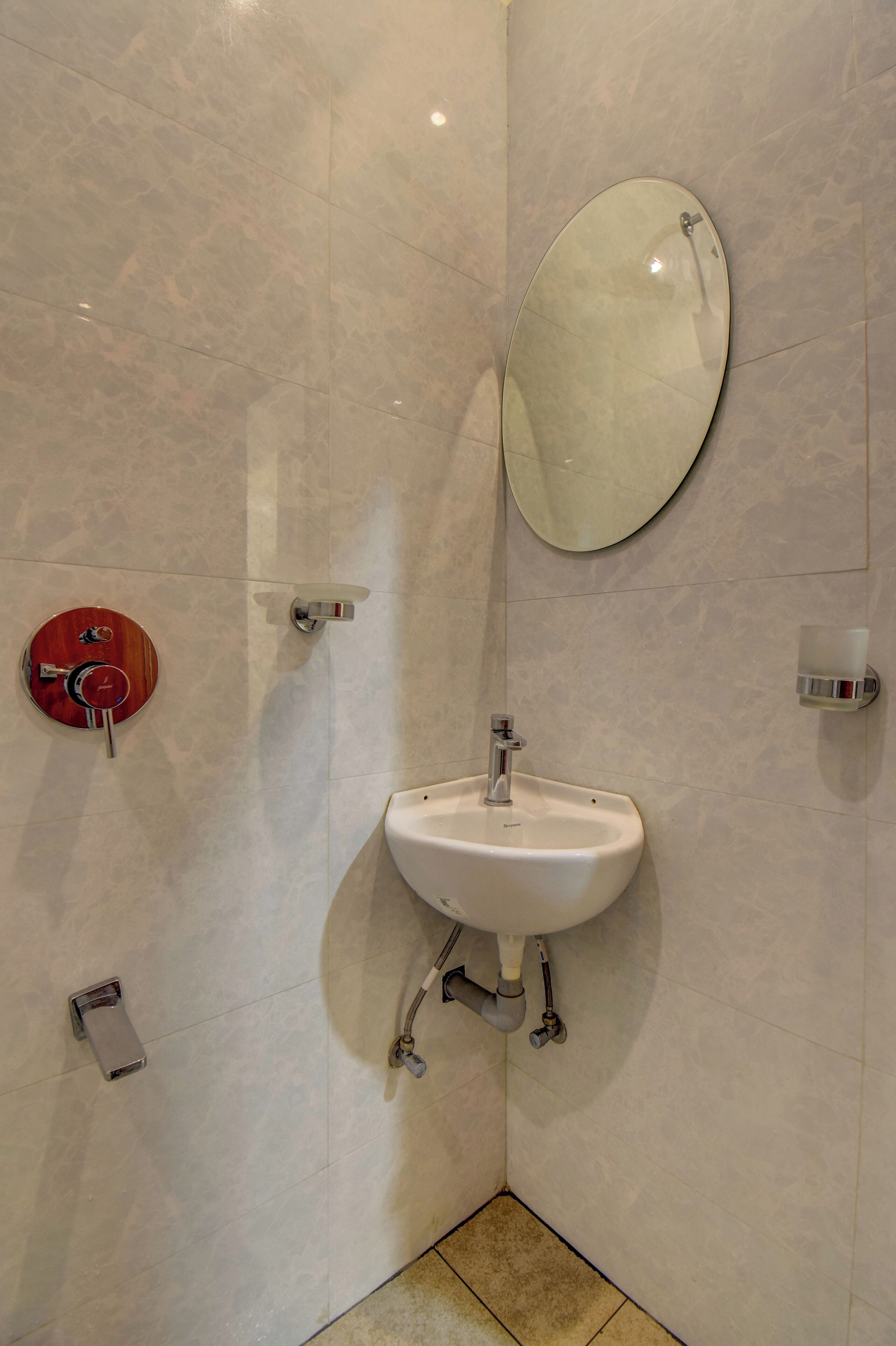 A bathroom with a white sink, a round mirror, and a red flush toilet.