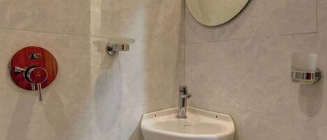 A bathroom with a white sink, a round mirror, and a red flush toilet.