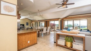 Una cocina amplia con una isla de madera, comedor con sillas, un sofá y un ventanal con vistas.