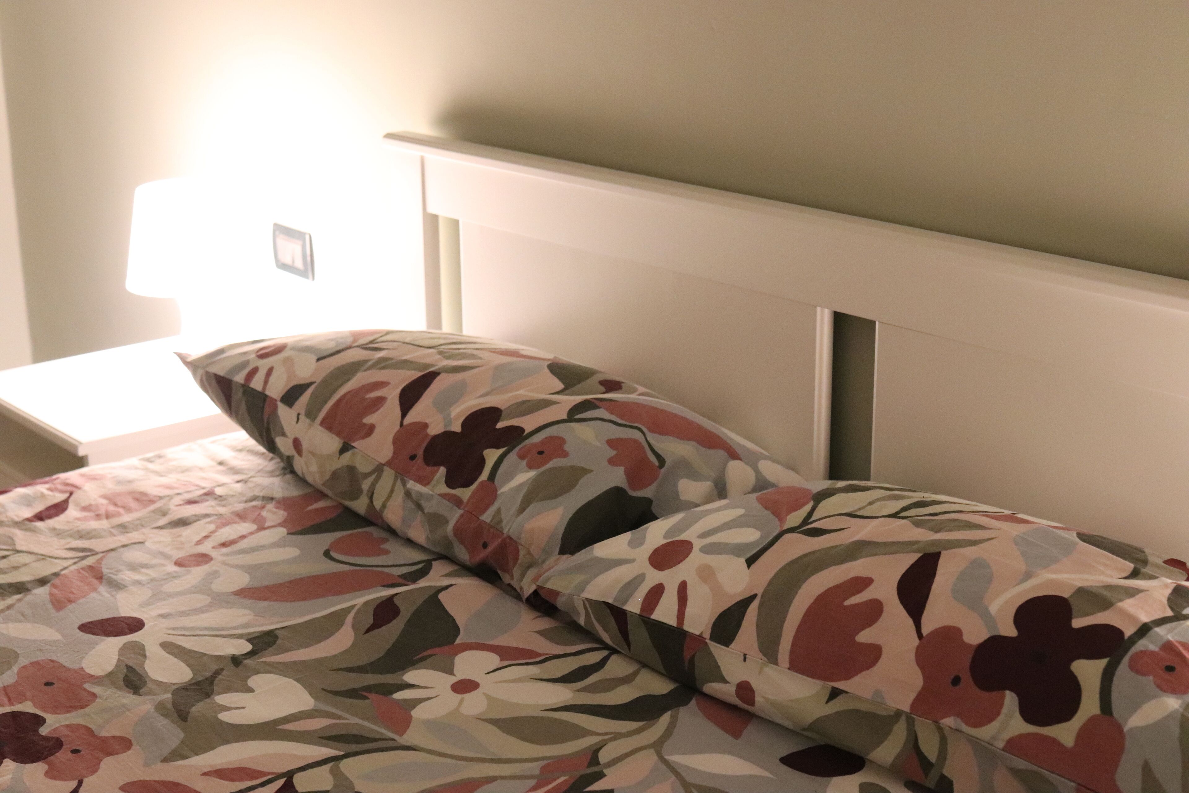 A bed with floral bedding and a white headboard.