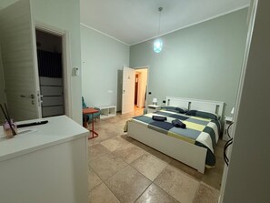 Un dormitorio con cama, escritorio, silla y una pequeña mesa.