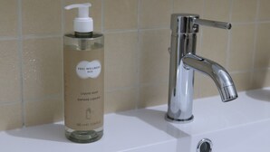 A bathroom with a chrome faucet and a bottle of liquid soap labeled "Feel Wellness ECO." - La casetta di Fra & Giu (Longobucco)
