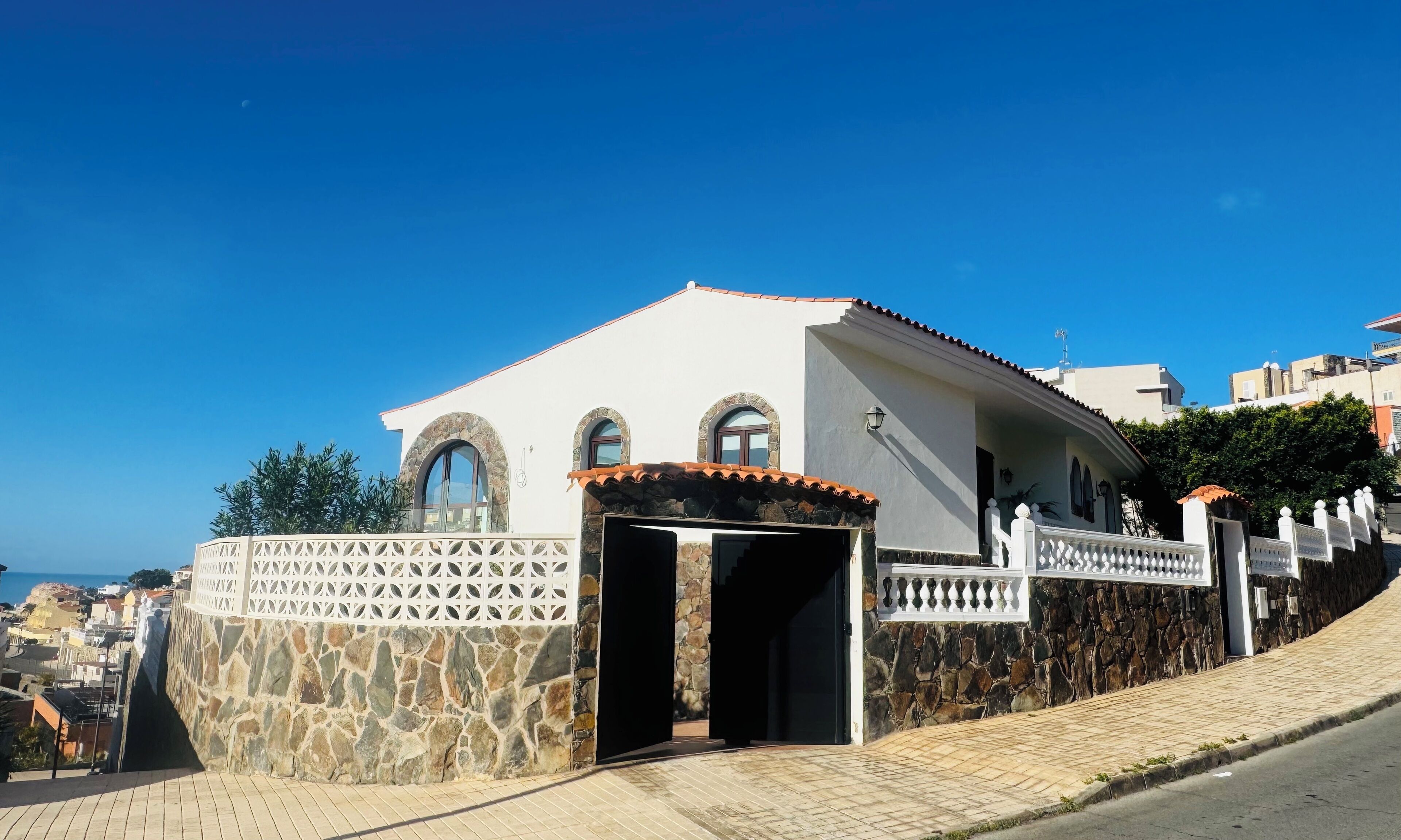 Un edificio costero con fachada de piedra, ventanas arqueadas y tejado de tejas.