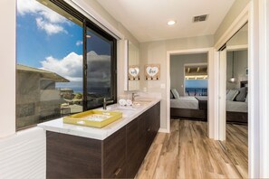 A modern bathroom with a large window, a vanity with a marble countertop, and a view of the ocean. - Kapalua Bay | Ocean View 5 BR, Sleeps 16 | Car Incl. w/ 6+ Nights | KBV ML-2032 by KBM (Lahaina)