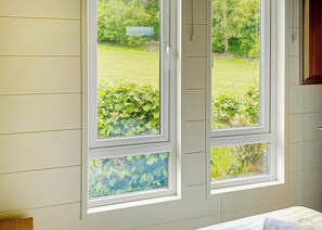 Ein Zimmer mit großem Fenster, einer Tür und Blick auf einen Garten.