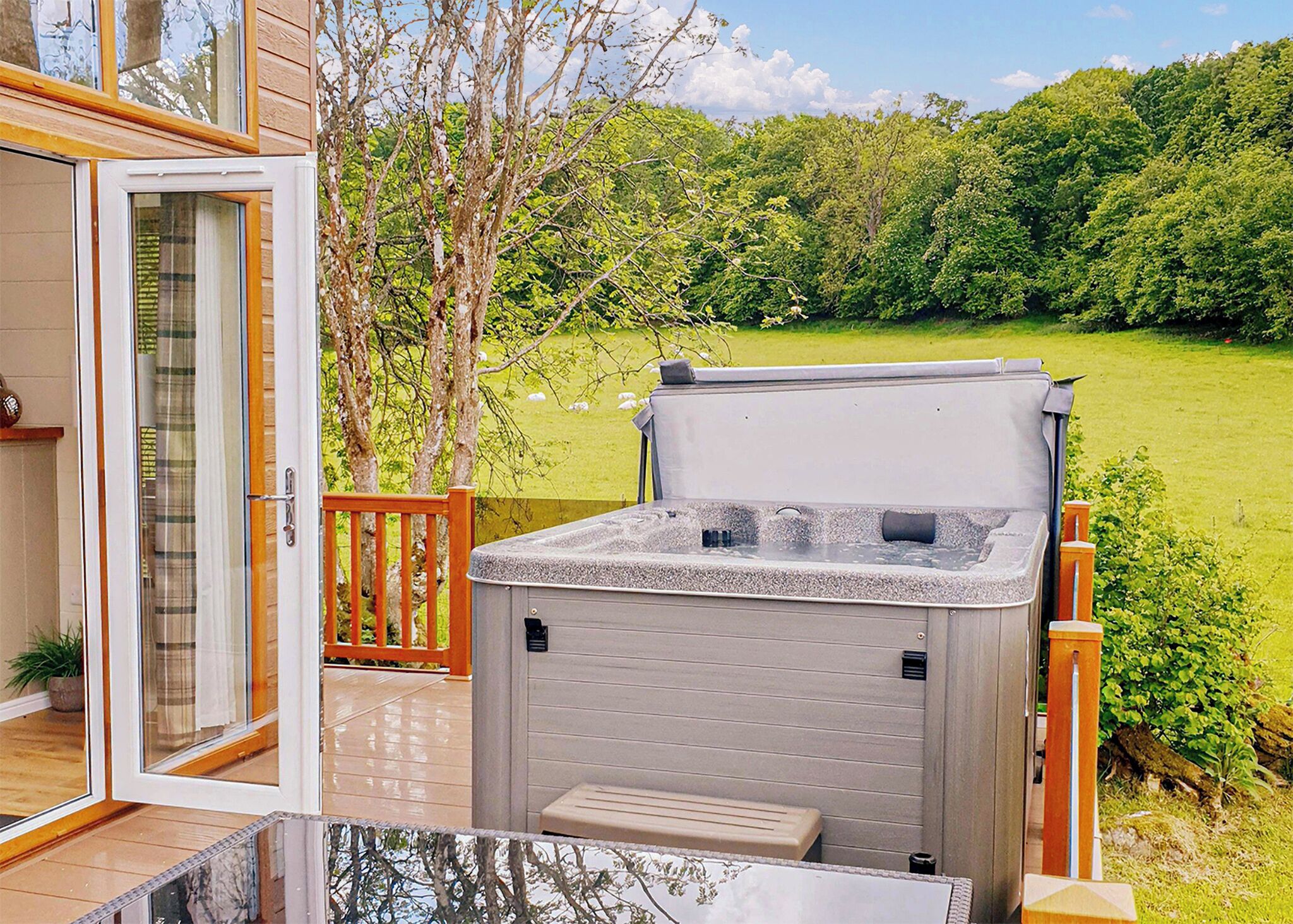 A hot tub on a deck with a view of a green landscape.