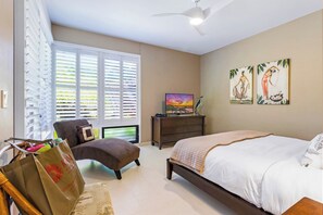 A bedroom with a bed, a chair, a dresser, a television, and artwork on the wall. - Kapalua Bay | Ocean View 5 BR, Sleeps 16 | Car Incl. w/ 6+ Nights | KBV ML-2035 by KBM (Lahaina)