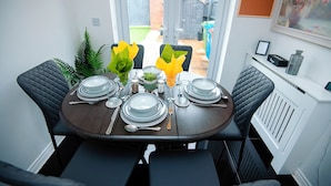 Mesa de comedor preparada para cuatro personas, con vista al jardín trasero.