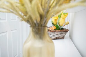 Eine weiße Tür, ein Korbwicker-Korb mit gelben Blumen und eine Vase mit getrockneten Pflanzen.