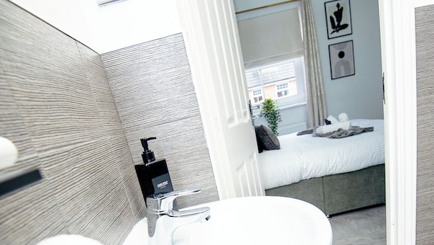 Un baño moderno con un lavabo blanco, un espejo y zona de ducha.