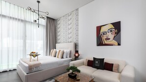 Een moderne slaapkamer met een bed, een bank, een bijzettafeltje en een schilderij aan de muur.