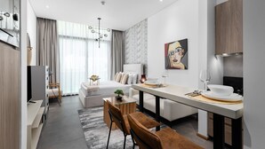 Een moderne hotelkamer met een zithoek, een bed, een televisie en een schilderij aan de muur.