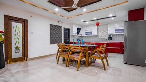 A modern kitchen with a dining area, featuring a wooden dining table and chairs, a refrigerator, and a patterned backsplash. - Crescent Stays T Nagar (Hyderabad)