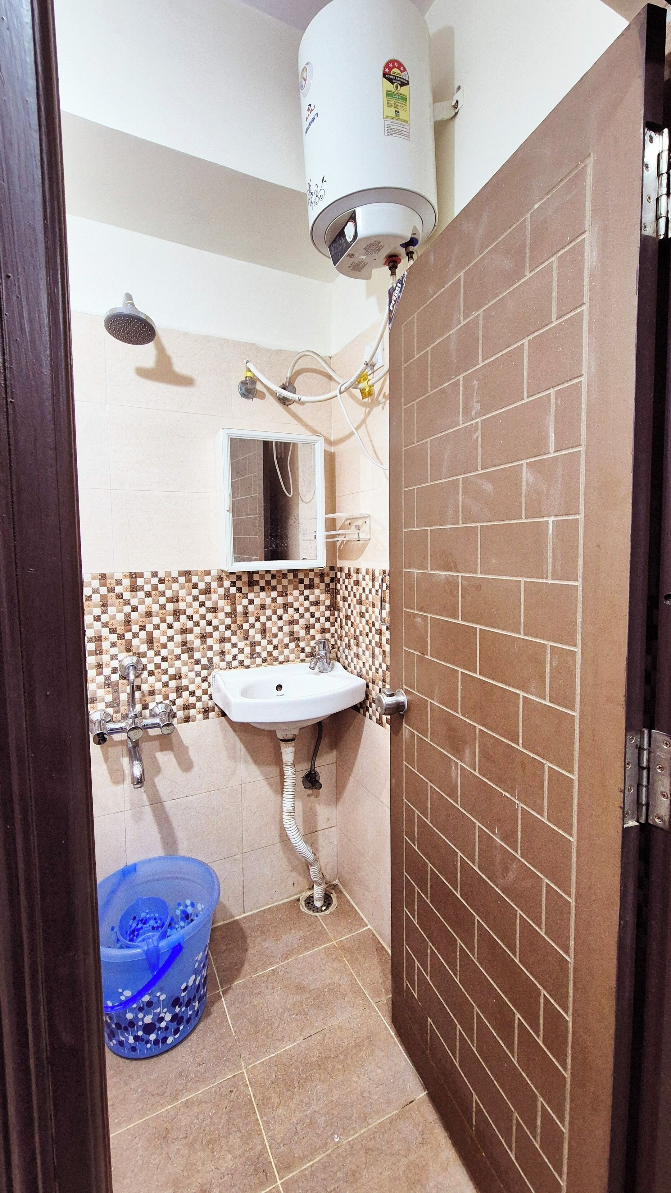 Een badkamer met een wastafel, spiegel, douche en een boiler.