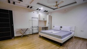 A bedroom with a bed, a ceiling fan, a drying rack, and a wardrobe. - Crescent Stays T Nagar (Hyderabad)
