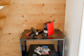 A small table with a red device and a black device on top, and a magazine on the table below. - Green Chalet - Wonderfull terrace lake view - Jacuzzi and SPA  (Dervio)