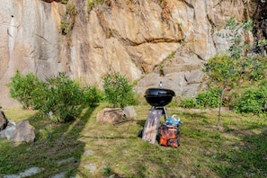 A portable grill set up outdoors with a bag of charcoal and a grill brush. - Green Chalet - Wonderfull terrace lake view - Jacuzzi and SPA  (Dervio)
