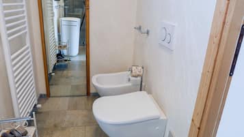 Une salle de bain équipée de toilettes, d’un bidet et d’un porte-serviettes.