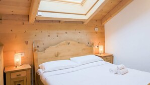 A neatly made bed with white linens and two bedside lamps. - Green Chalet - Wonderfull terrace lake view - Jacuzzi and SPA  (Dervio)