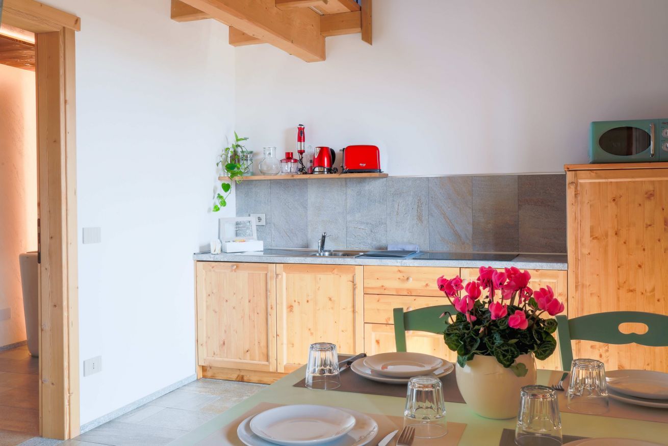 Eine Küche mit Holzausstattung, einem Spülbecken und einer Essecke mit Tisch für zwei Personen.