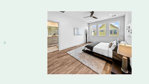 Ein modernes Schlafzimmer mit Bett, Nachttisch und Blick auf ein Haus durch das Fenster.
