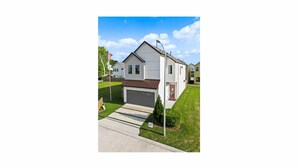 Einbungalow mit Garage, rotem Eingangstür und kleinem Vorgarten mit Fahnenmast und Rasen.
