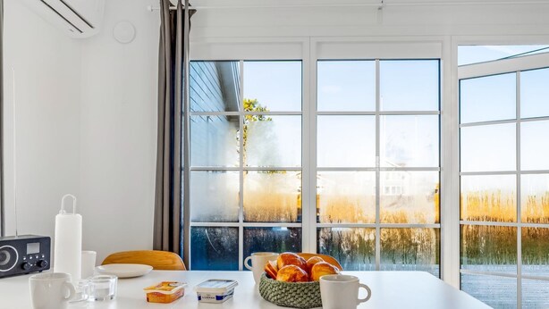 A breakfast table with a radio, a bowl of croissants, and a view of a field through large windows. - "Ama" - 350m from the sea by Interhome (Læsø)