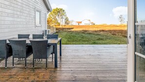 A deck with a table and chairs, a grassy area, and a building in the background. - "Ama" - 350m from the sea by Interhome (Læsø)