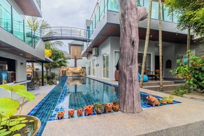 A modern hotel with a swimming pool, outdoor seating, and tropical plants. - Modern 10BR ZipLine 3 Pools  V256 (Rawai)