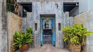 A concrete entrance with a blue door, flanked by two large potted plants. - Modern 10BR ZipLine 3 Pools  V256 (Rawai)