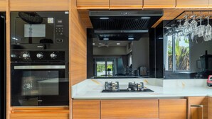 A modern kitchen with built-in appliances, a central island, and a view of the outdoors. - Modern 10BR ZipLine 3 Pools  V256 (Rawai)