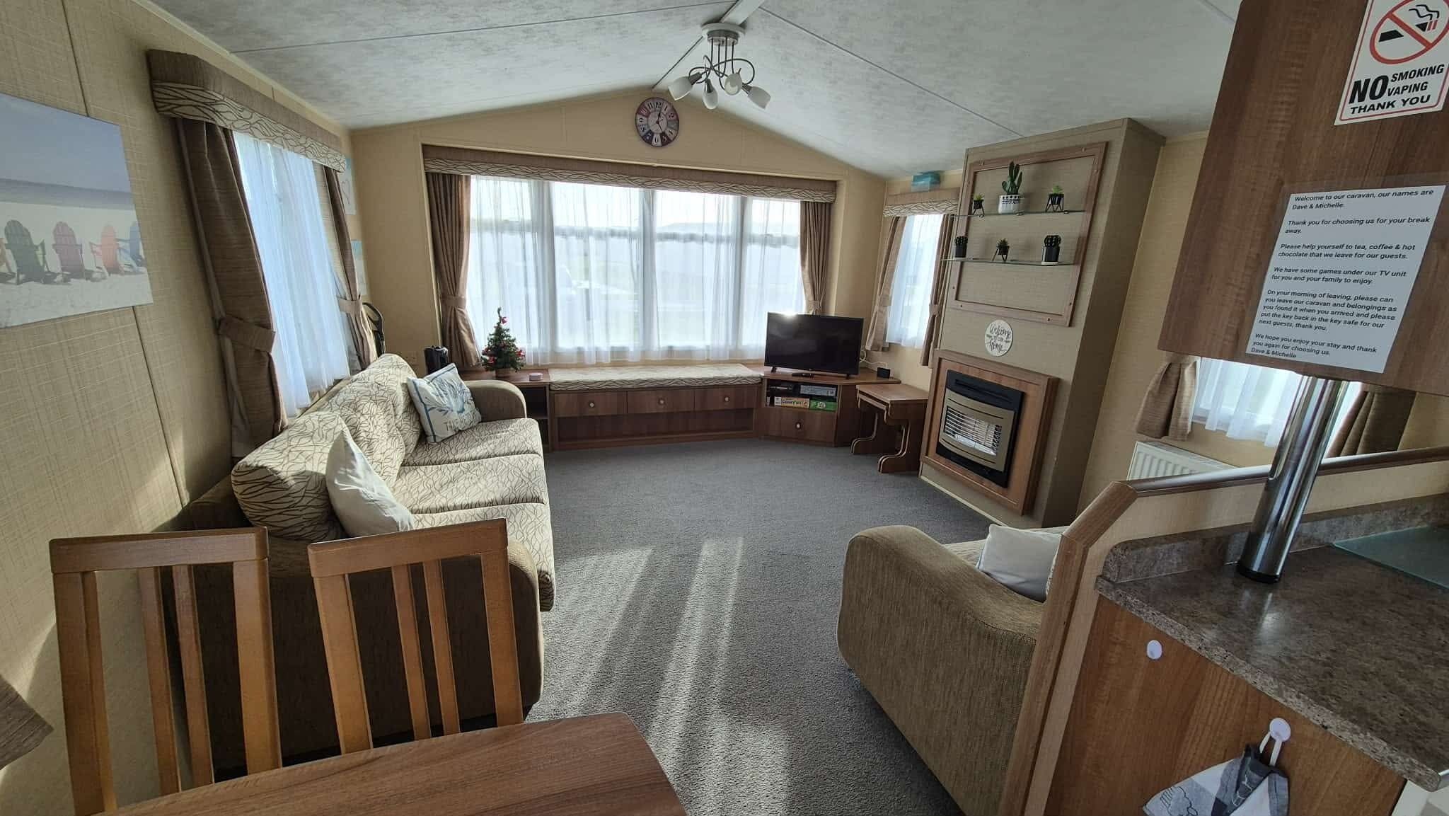 Un intérieur de caravane accueillant, avec un canapé, un téléviseur et une petite table.