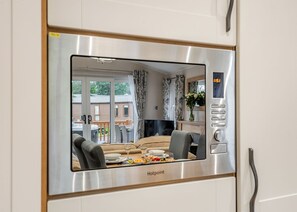 A modern kitchen with a built-in microwave, a dining area with a table and chairs, and a view of the outside. - 2 bedroom accommodation in Bala, (Bala,)