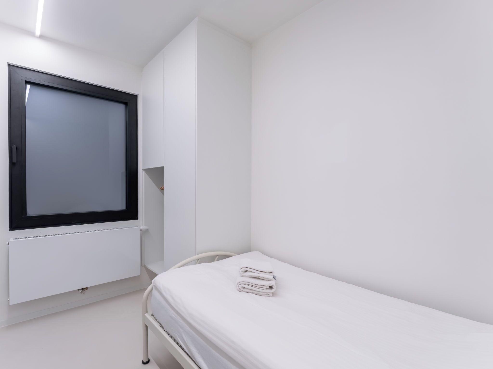 A small, clean room with a single bed, a window, and a radiator.