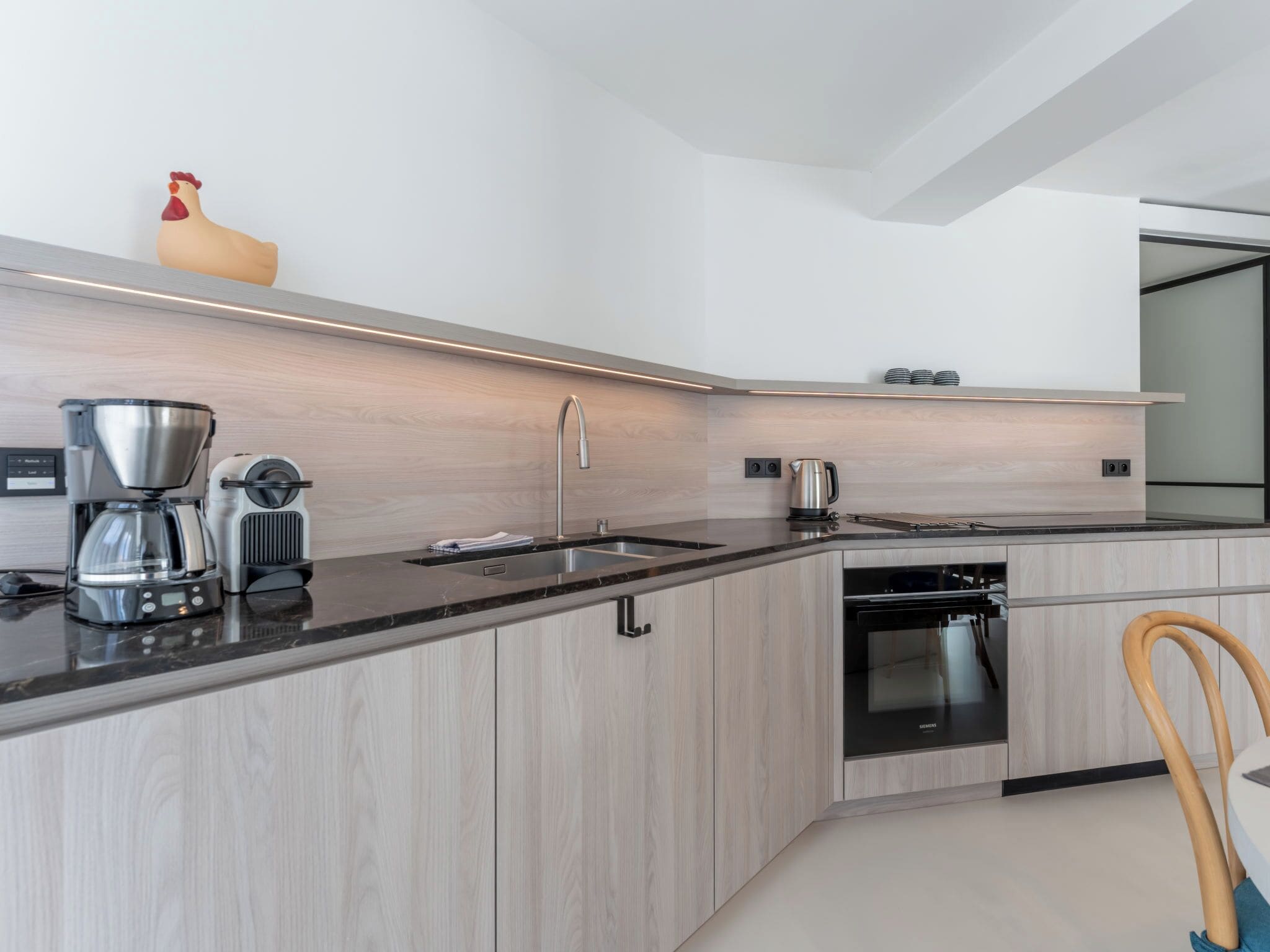 A modern kitchen with a built-in oven, a coffee maker, and a kettle.