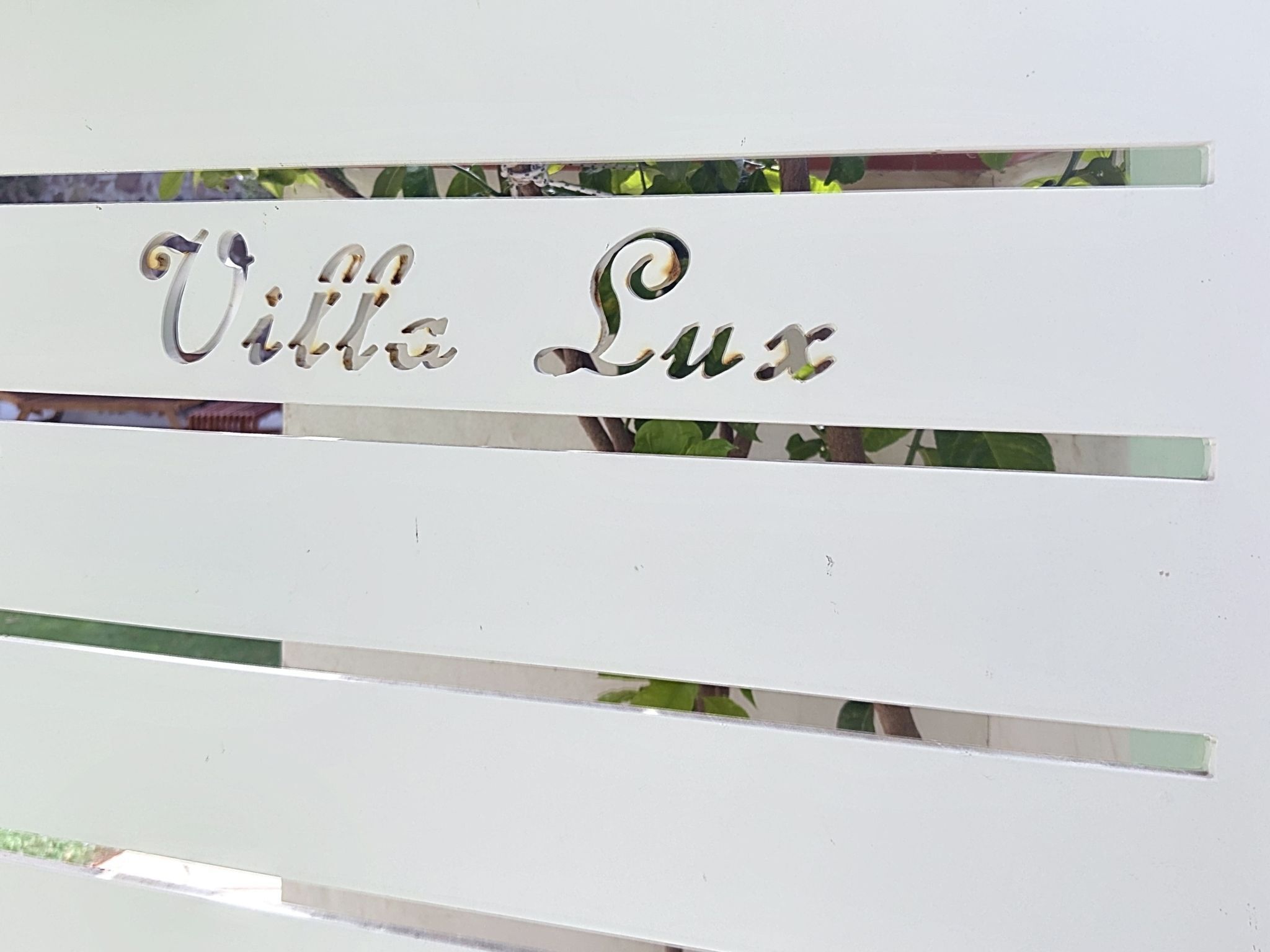 Un cartello bianco con la scritta 'Villa Lux' in un font decorativo.