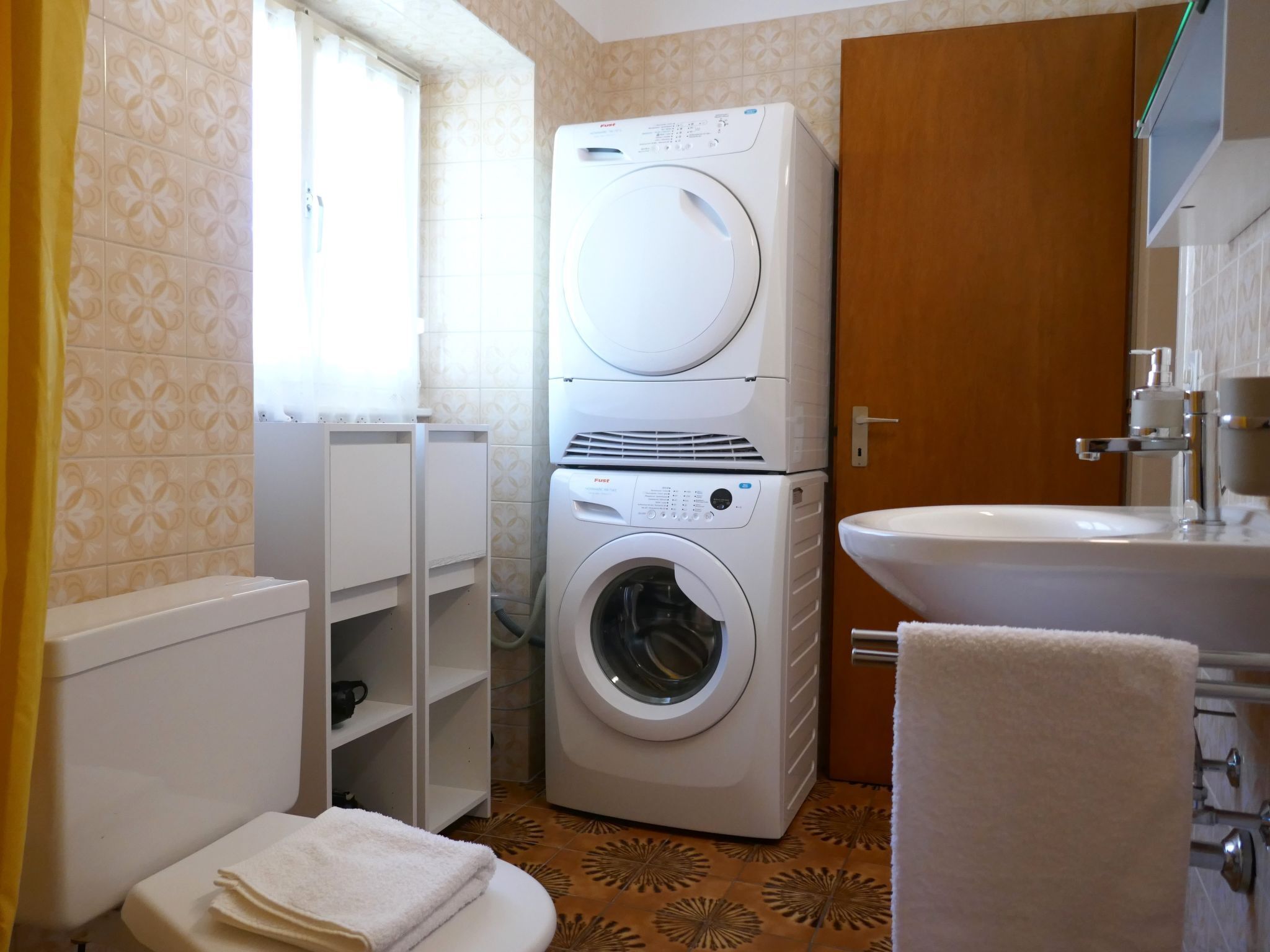 A compact bathroom with a washing machine, a toilet, and a sink.