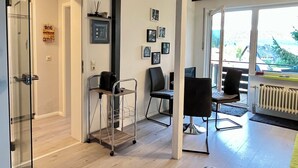 Ein modernes Zimmer mit Glastür, einer Kaffeemaschine, einem Sessel und einem Tisch.