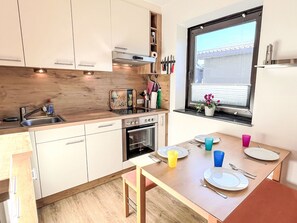 Een koelkast, een oven, kookgerei, borden en bestek