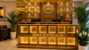 Un comptoir d’accueil avec une enseigne « JMD Hotels », un ordinateur et un panneau d’accueil.