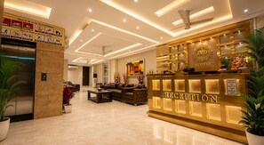 Un espace d’accueil d’hôtel comprenant un comptoir de réception, un coin salon avec des canapés et une œuvre d’art accrochée au mur.