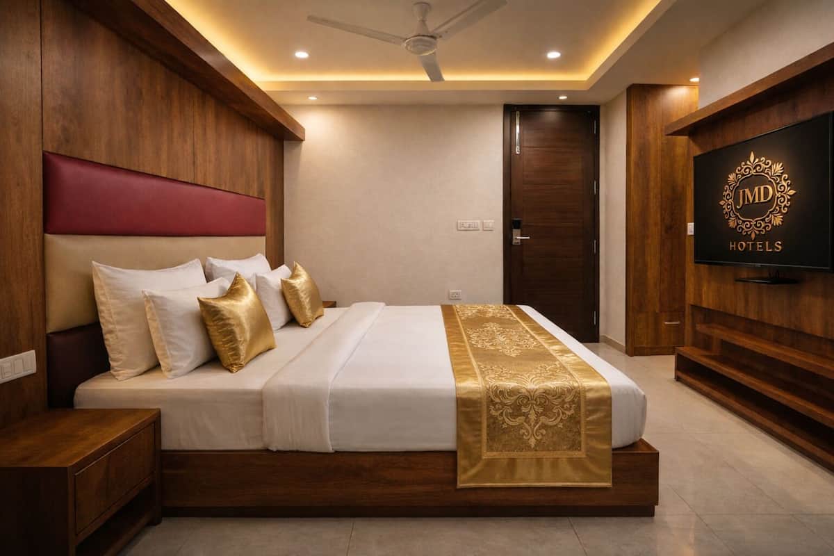Una habitación de hotel moderna con una cama grande, cabecera de madera y un televisor en la pared.