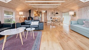 Amplia sala de estar con techo alto, paredes de madera y tragaluces.