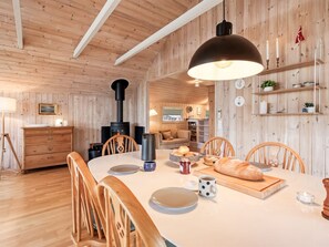 A cozy wooden interior with a dining table set for four, a fireplace, and a kitchen area. - "Athislus" - 1.1km from the sea by Interhome (Glesborg)