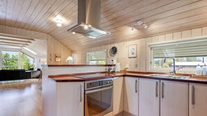 Una cocina moderna con armarios de madera, una campana extractora de acero inoxidable y un ventanal grande.