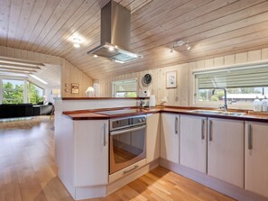 A modern kitchen with wooden cabinetry, a stainless steel range hood, and a large window. - "Athislus" - 1.1km from the sea by Interhome (Glesborg)