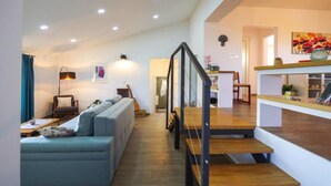 Una sala moderna con un sofá, una mesa de centro y una escalera que lleva a una zona de cocina.
