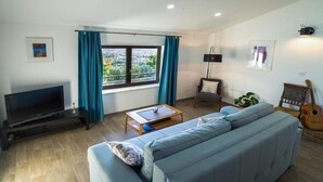 Una sala de estar con sofá, televisión, mesa de centro y una guitarra.
