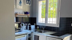 A modern kitchen with white cabinets, a Bosch dishwasher, a microwave, and a sink. There is a window with a view of greenery outside. - Detached studio with terrace in Aix countryside property (Aix-en-Provence)