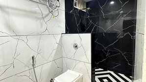 A bathroom with a toilet, a water heater, and a black and white patterned floor. - Hotel Rajshree Inn (Ujjain)